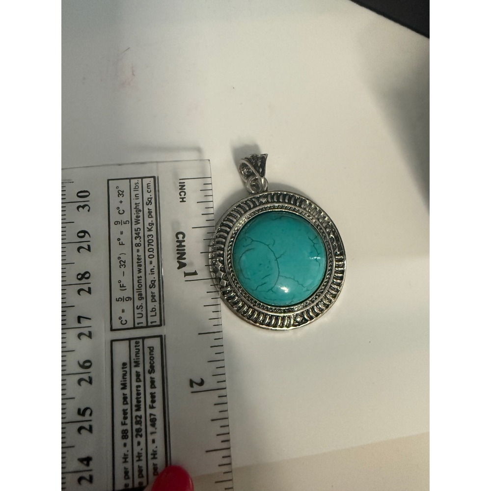Turquoise Colored Stone Pendant Set In Ornate Textured Silver Tone Metal Frame